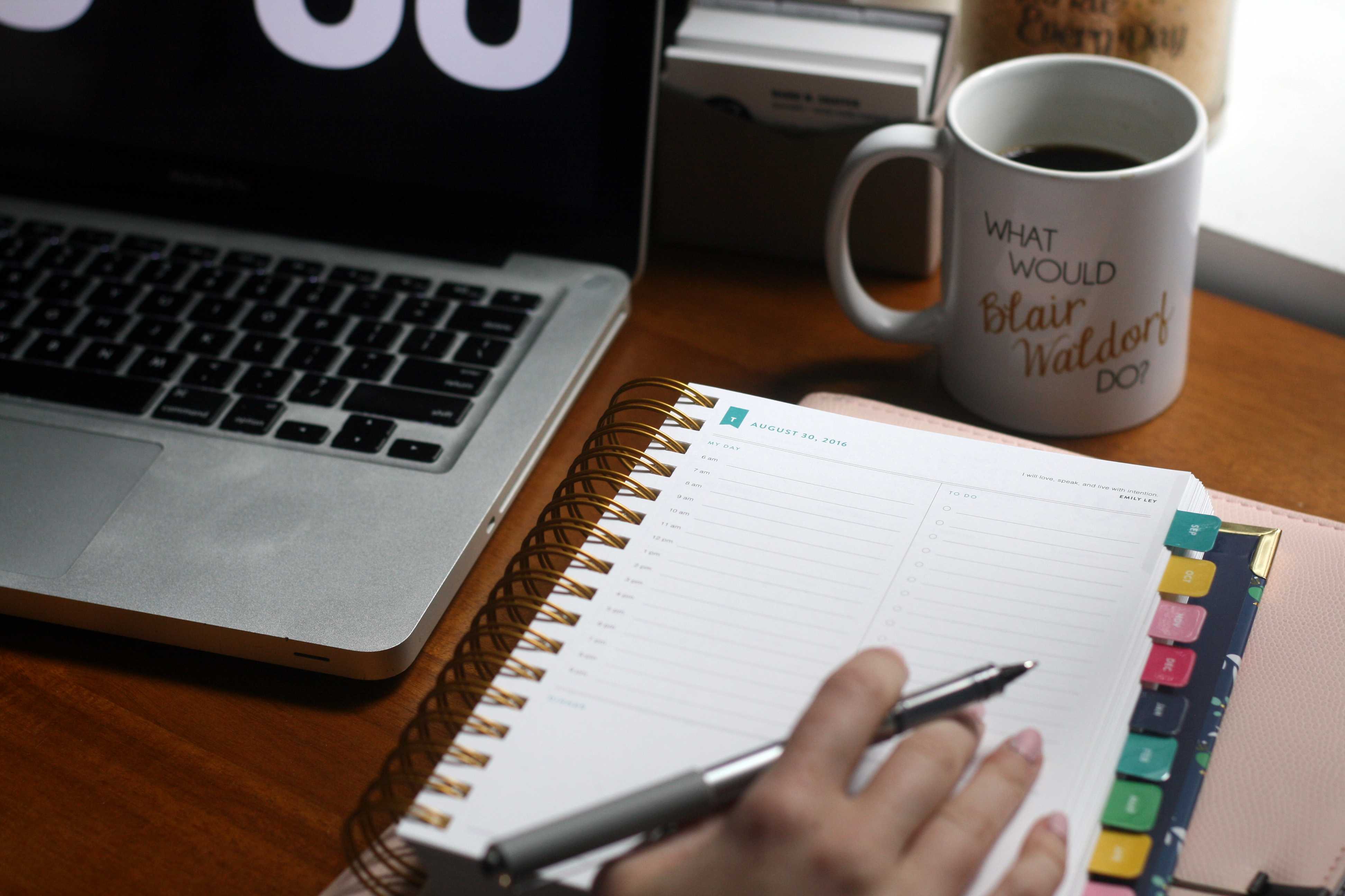 Person at a desk preparing a weekly plan with sticky notes and a cup of tea